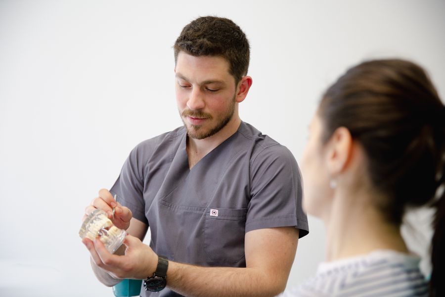 Dentista explicando un tratamiento con un modelo dental a la paciente